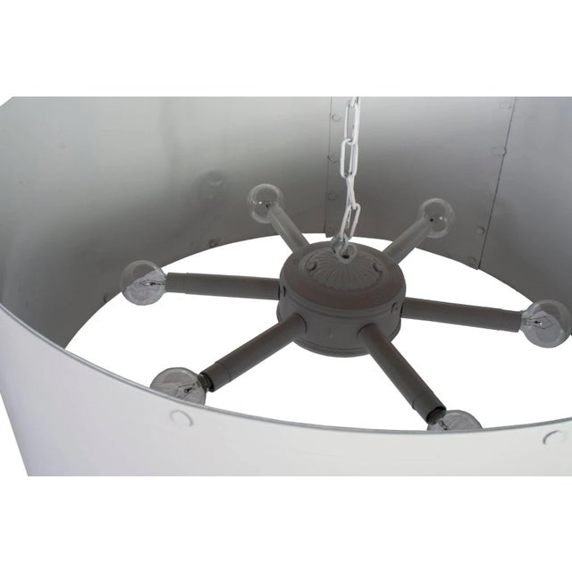 This large round French industrial metal chandelier features a classic white color and a sleek design, adding a touch of...