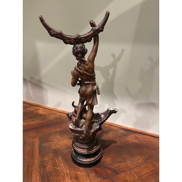A beautifully aged antique spelter figure mounted on a turned wood base, offered as an evocative piece of architectural...