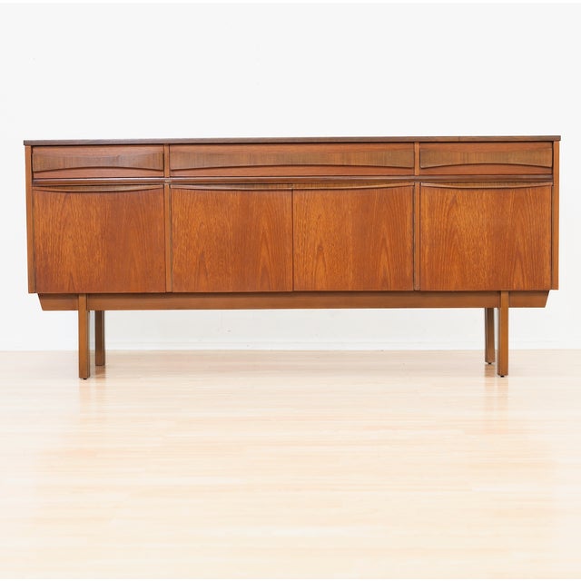 This elegant mid-century British teak credenza showcases clean lines and beautifully sculpted handles that flow seamlessly...