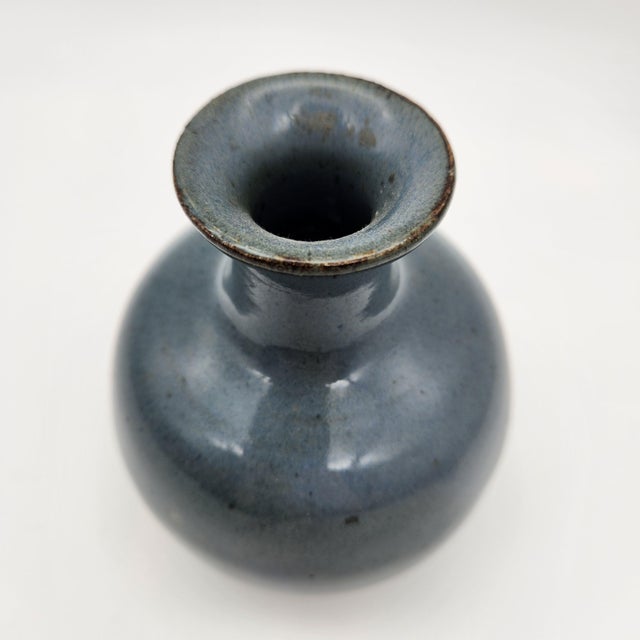 Studio pottery weed pot with bulbous body, flared neck, and smooth blue-gray glaze with iron-oxide rim