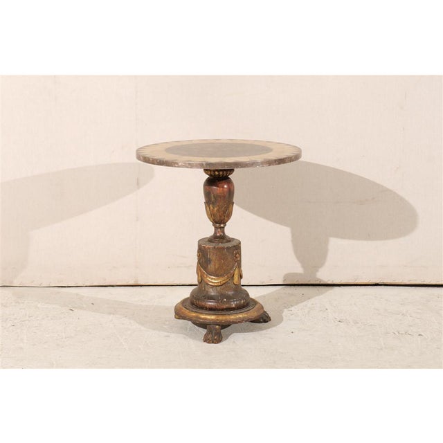 An Italian round occasional table with 18th century paw feet, painted and gilded wooden base decorated with carved swags...