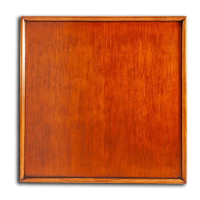 This square coffee table features a richly finished wood surface with a warm, traditional appearance. A raised gallery...