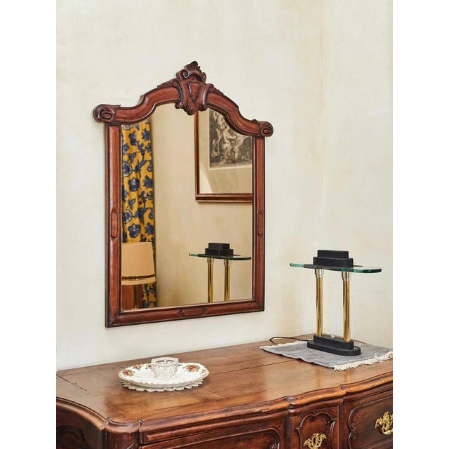 Elegant wall mirror with a hand-carved frame made of solid wood. The frame is decorated with stylized ornaments and a top...