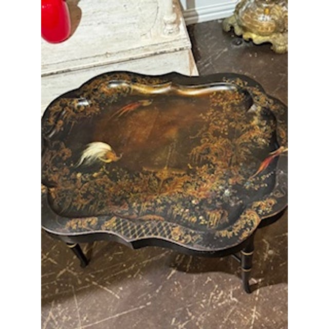 The product is an early 20th century English tole low table. This low table showcases a classic design and craftsmanship...