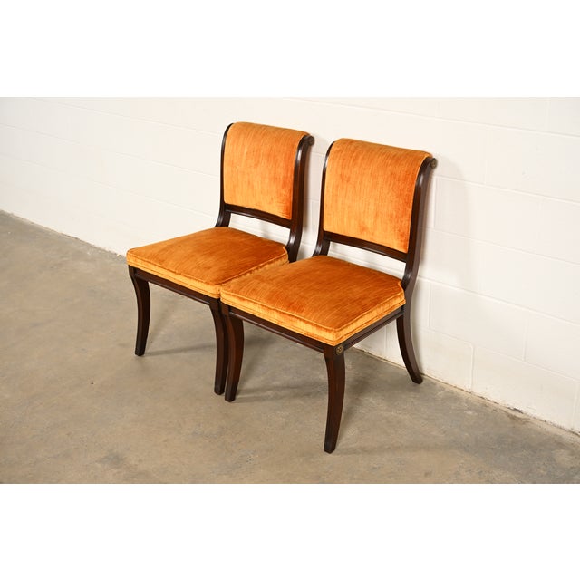 A gorgeous pair of Regency style side chairs or dining chairs By Kittinger USA, Circa 1960s Carved mahogany frames, with...