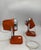 A pair of 1970s-style adjustable space-age table lamps, featuring a conical body in orange lacquered metal and a polished...