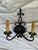 Matching set of black wrought iron two arm sconces with scrollwork backplates and beeswax-style candle covers.