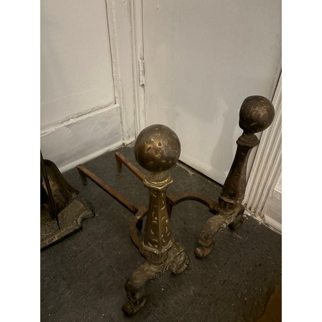 A handsome early 20th-century cast iron fireplace ensemble featuring a matching pair of substantial andirons and...