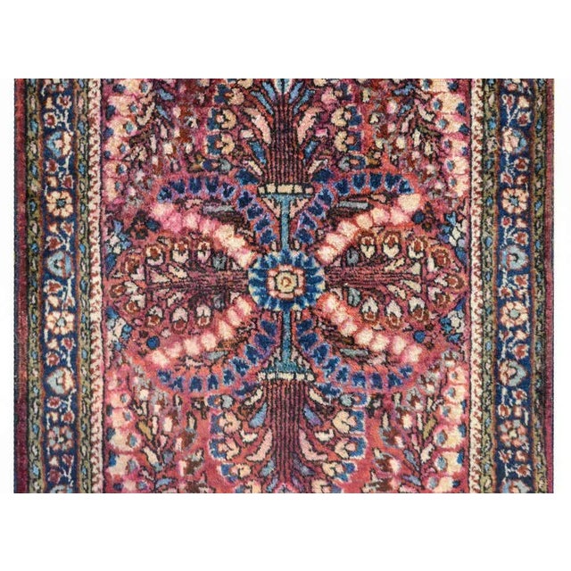 A beautiful early 20th century Persian Sarouk rug with a mirrored tree-of-life pattern woven in cream, cranberry, light...