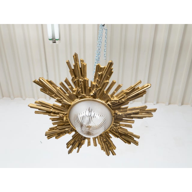 A pair of Midcentury gilt bronze sunburst semi-flush light fixtures with frosted glass bottom concealing the light...