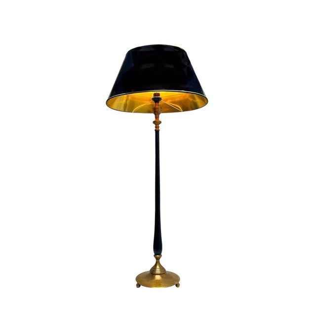 Neoclassical floor lamp in brass and black-lacquered metal. The subtly detailed round brass base rests on three ball-...