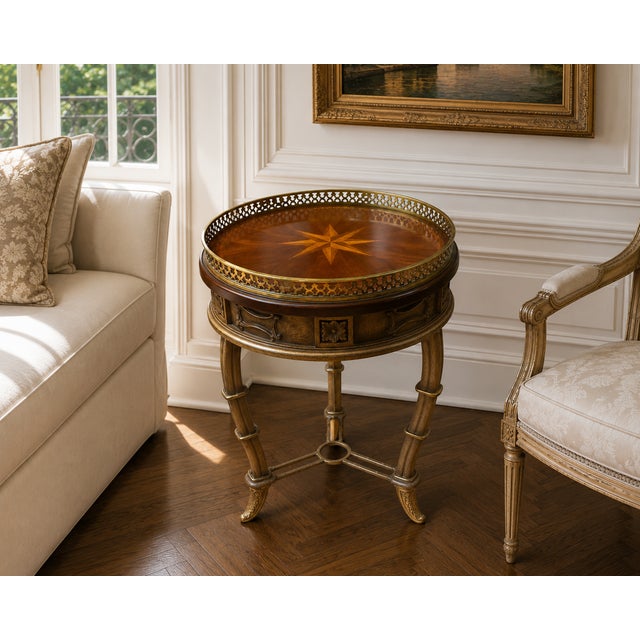 A handsome Regency-style round accent table featuring a rich mahogany finish, an elegant brass gallery, and a decorative...