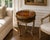 A handsome Regency-style round accent table featuring a rich mahogany finish, an elegant brass gallery, and a decorative...