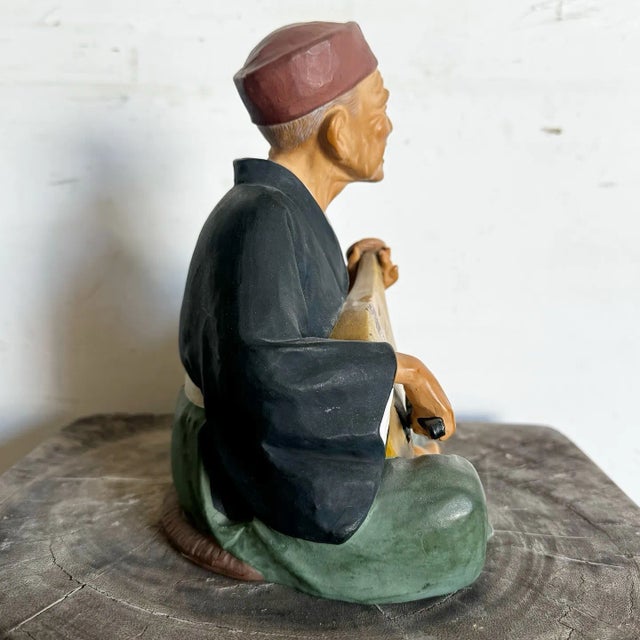 This vintage Japanese clay figurine by Lefton’s depicts an elderly musician seated cross-legged while playing a biwa,...