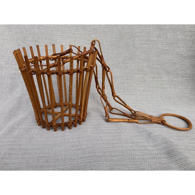 Mid Century rattan hanging basket. Great condition. It measures overall 7 1/4" in diameter by 24 1/2" in height. The...