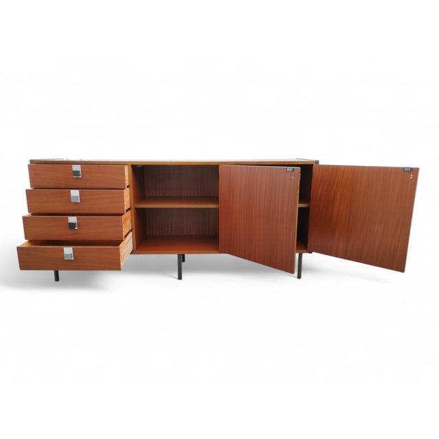Sideboard in teak veneered wood, 1960s. Equipped with four drawers and two doors with shelves inside. Legs in black...