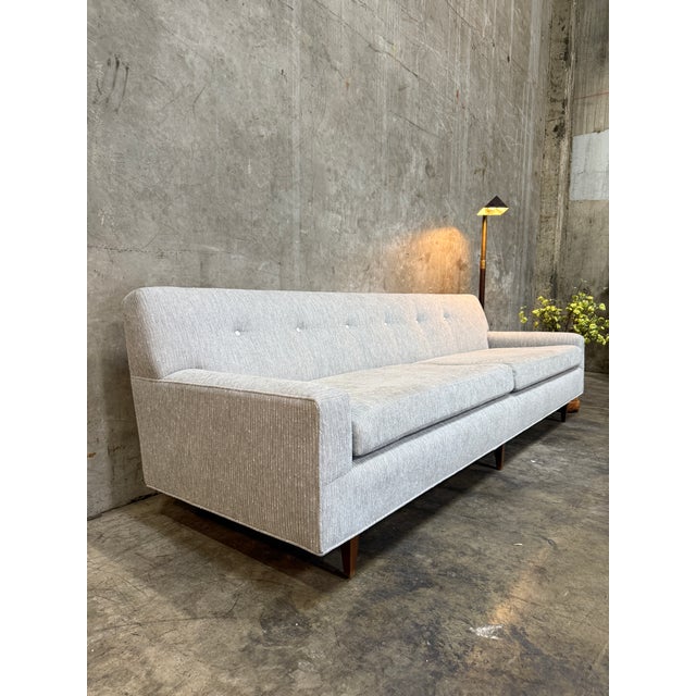 A beautifully restored 1960s mid-century modern sofa, fully reupholstered in a soft, textured neutral fabric with refined...