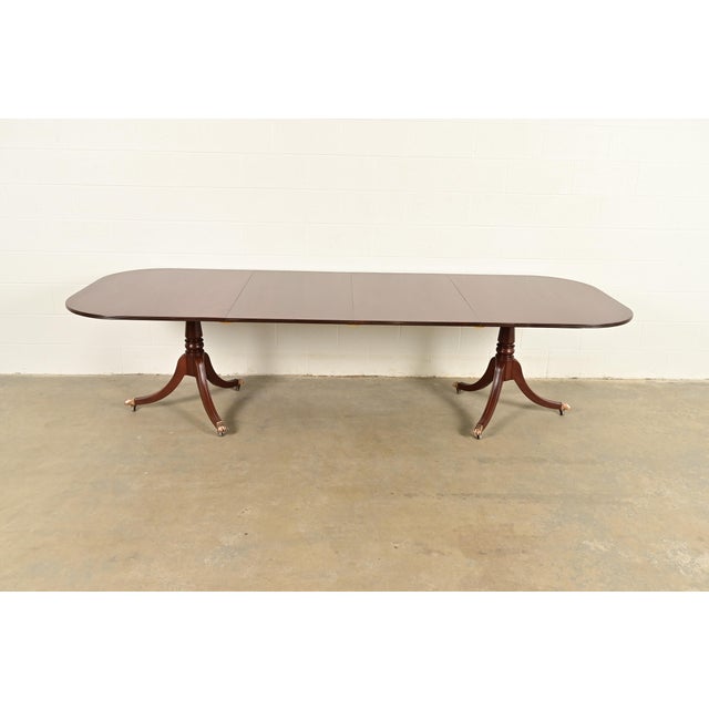 An exceptional Georgian or Regency style double pedestal extension dining table In the manner of Baker Furniture USA,...