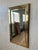 A striking Hollywood Regency wall mirror featuring a substantial brass frame with a beautifully inset beveled mirror...