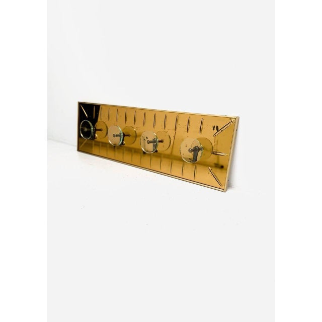 A rare and impressive wall-mounted coat and hat rack by cristal art, featuring a stunning gold-colored glass panel with...