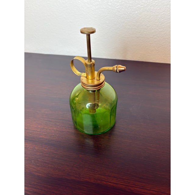 This vintage mister, spray bottle made of green glass that stands 6 inches tall and has a brass handle which spritzes...