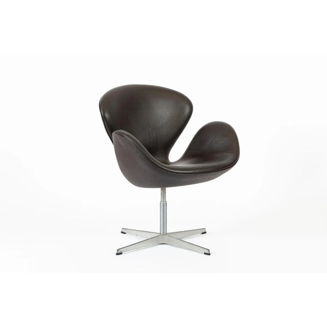 This brown mid century Danish modern Swan chair by Arne Jacobsen for Fritz Hansen was made in Denmark and produced in...