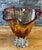 An exquisite fan-shaped art glass vase, meticulously hand-blown from a rich spectrum of amber glass, resulting in a...