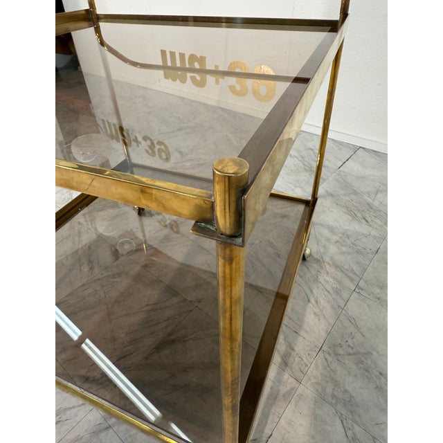 The golden brass frame and smoked glass shelves, paired with petite caster wheels, give this vintage Italian bar cart its...