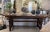 Hand-shaped and sanded smooth, this console table shows off walnut in natural wood, its surface carrying the quiet...