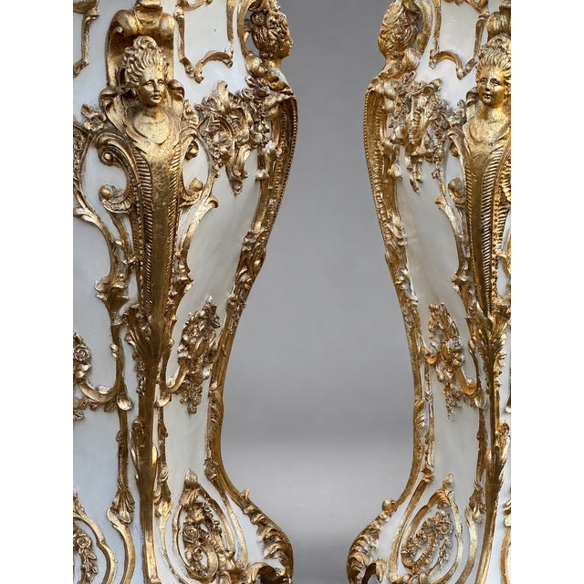 A highly decorative pair of late 20th-century Italian Baroque Revival pedestals, finished in an elegant cream tone with...