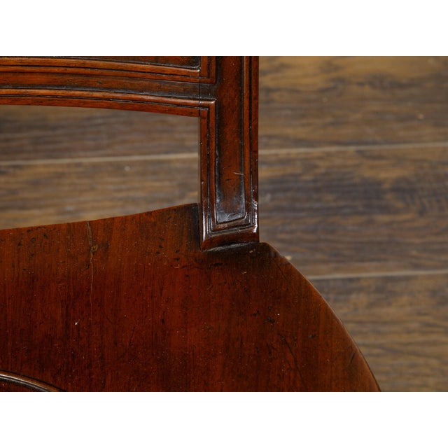A pair of English Regency mahogany hall chairs from the 19th century with coat of arms, dished seats and saber legs. These...