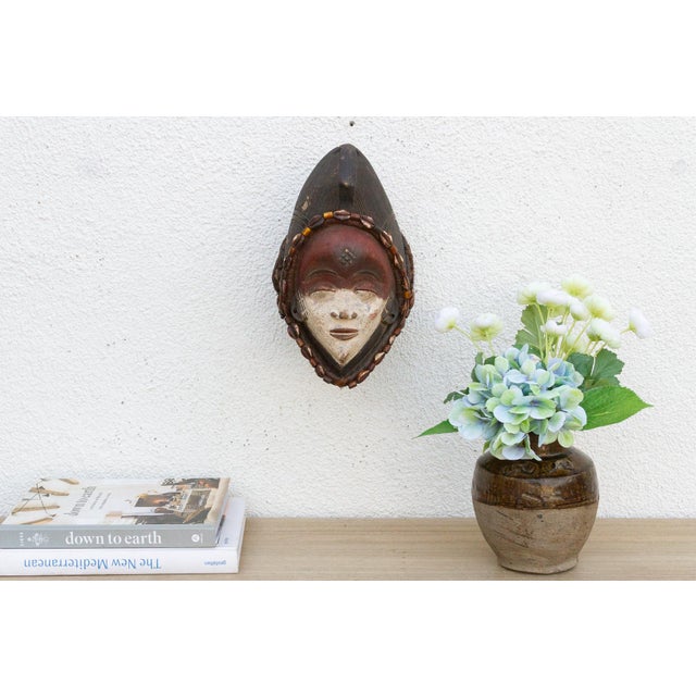 Discover the captivating allure of authentic African art with this vintage hand-carved wooden mask. Imbued with a rich...