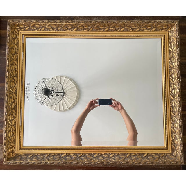This stunning mirror features a gold-colored wooden frame, measuring approximately 34” in width, 28” in length, and 2” in...