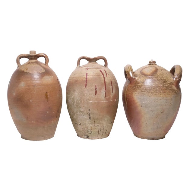 A beautifully cohesive set of three French provincial oil jugs, hand-thrown in terracotta and fired with natural ash and...