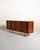 Danish-made teak sideboard from the 1960s, featuring three sliding doors and five side drawers. The front is accented by...