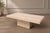 A substantial travertine coffee table with a clean rectangular top and solid pedestal base. The natural stone has...