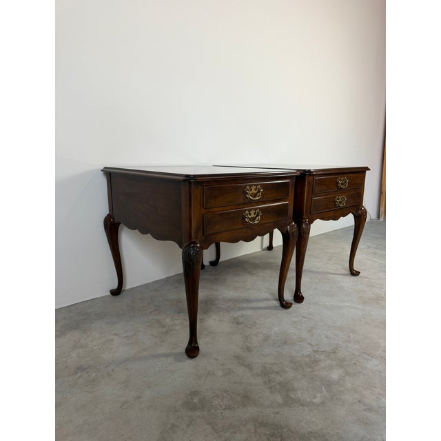 Beautiful pair of vintage Drexel nightstands featuring a warm finish, dovetailed drawers, brass bail pulls, scalloped...