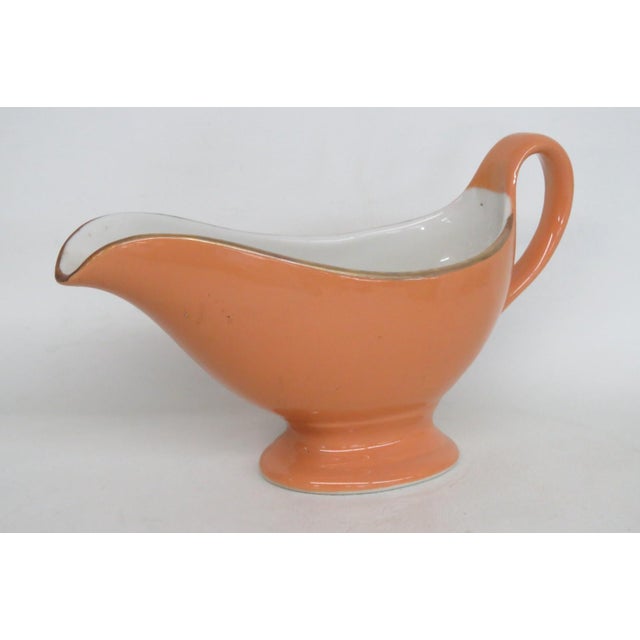 This beautiful footed Gravy Boat is made of Ceramic. This lovely orange colored ceramic piece was made by Shenango China...