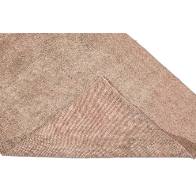 Beautiful vintage Turkish hand knotted wool rug with a peach field. This rug has tan accents in a gorgeous all-over...