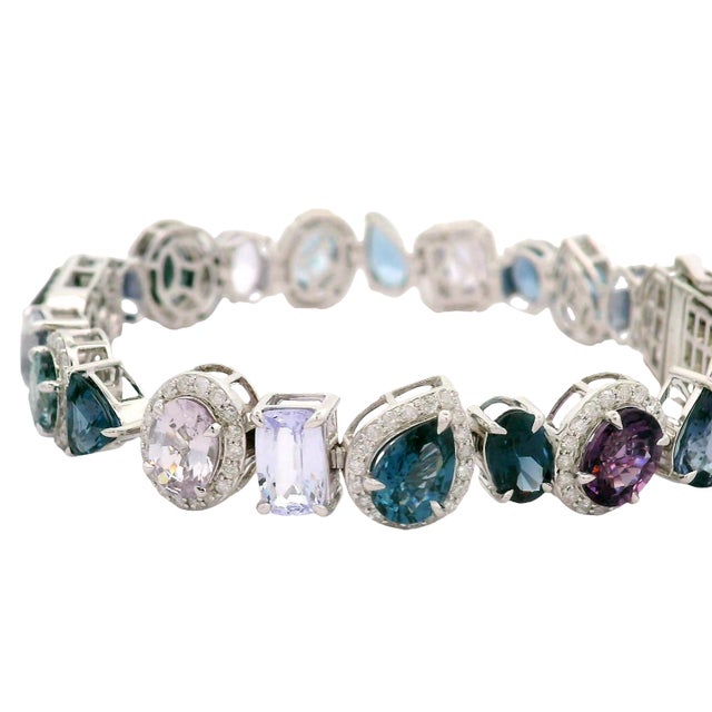 This elegant tennis bracelet features a stunning mix of multi-cut spinel gemstones in different color tones, each framed...