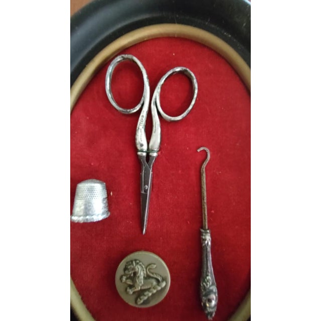 Framed antique silver sewing kit. The kit is comprised of sterling embroidery scissors, antique silver button/shoe hook...