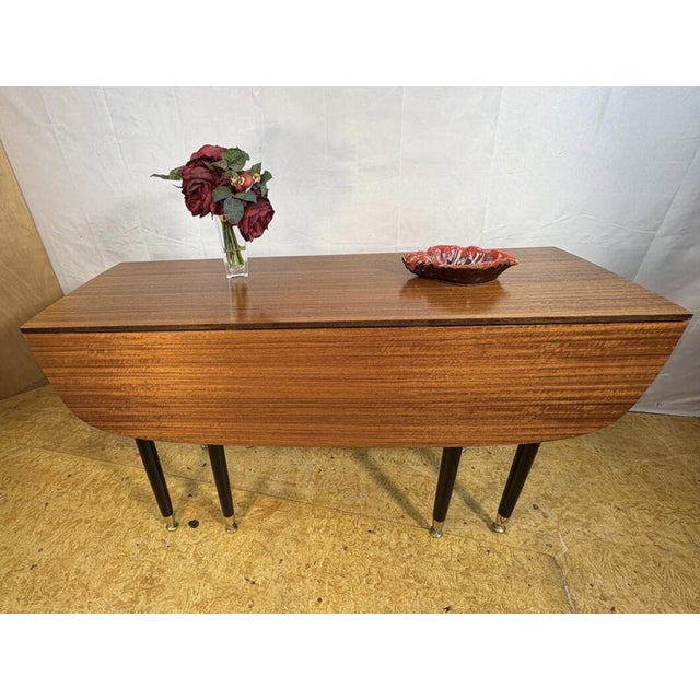A stunning and iconic mid century modern folding extending dining table by g-plan, dating from the 1950s and originating...