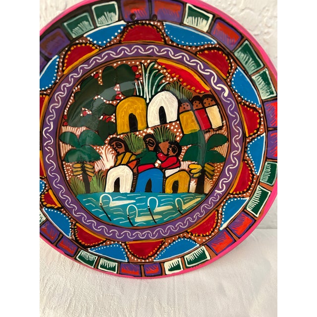 Vibrantly colorful pair of hand-painted pottery plates each depicting a folk community scene. Excellent condition. Holes...