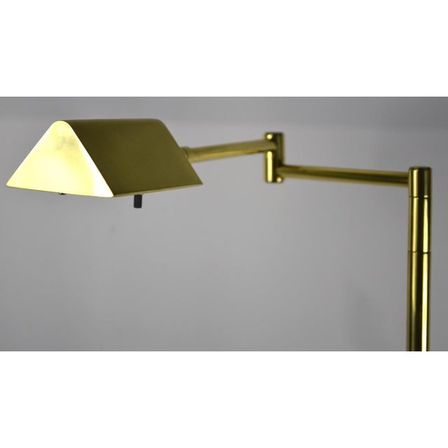 A pair of modernist brass floor lamps, circa 1970's/1980's. Lamps have reticulated swing arms and sport a halogen bulb....