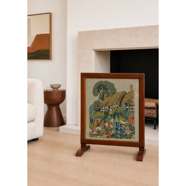Antique needlepoint fire screen featuring a picturesque thatched cottage garden scene, hand-stitched with rich, softly...