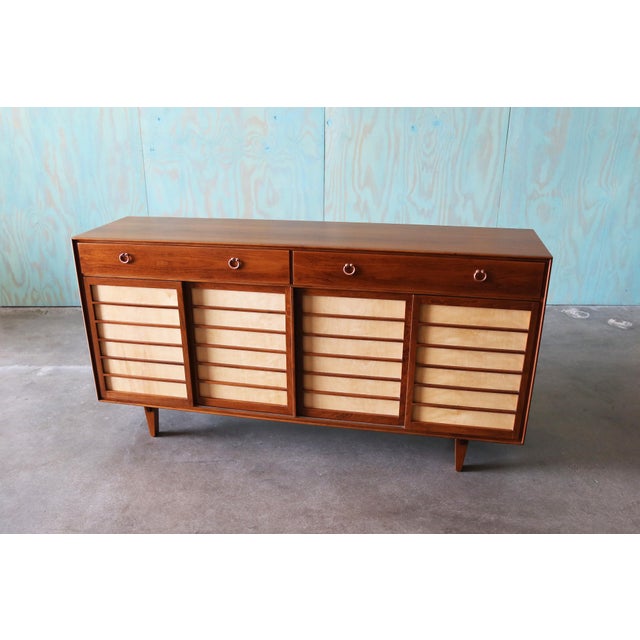 A two tone walnut and birch cabinet by Edward Wormley for Dunbar circa 1950s, part of the Janus Line. Featuring open...