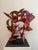 A dynamic abstract steel sculpture in high-gloss crimson, combining industrial textures with sweeping geometric forms to...