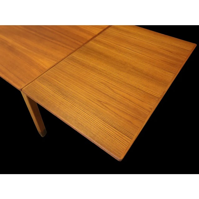 A teak dining table with a golden tone. The table is designed by Omann Jun, Denmark. A relatively unusual model that is...