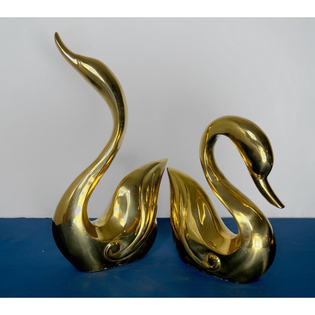 A commanding pair of monumental Hollywood Regency brass swan sculptures with exceptional sculptural styling and dramatic...