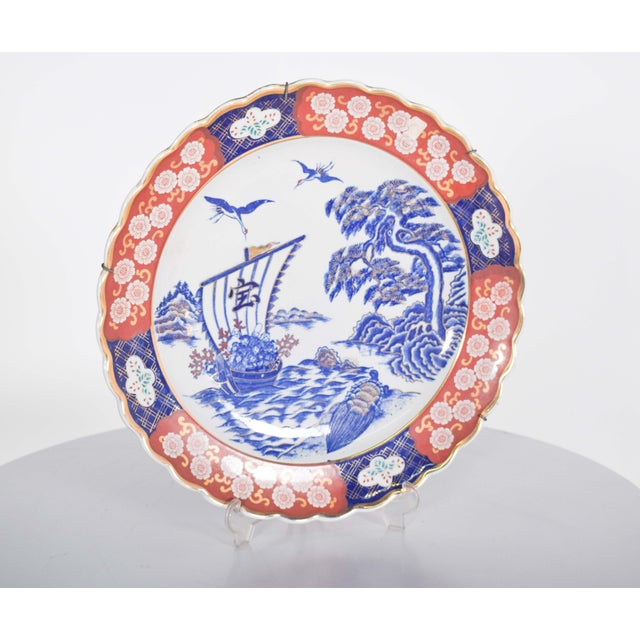 A beautifully crafted cut-out porcelain plate, adorned with vibrant shades of blue, red, white, and gold trim. The front...